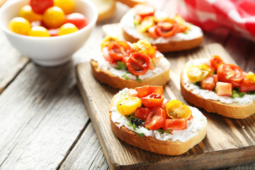 Tasty fresh bruschetta with tomatoes on cutting board on grey wo