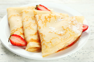 Pancakes with strawberry on plate on white wooden backgound