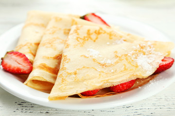 Pancakes with strawberry on plate on white wooden backgound