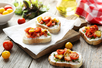Tasty fresh bruschetta with tomatoes on cutting board on grey wo
