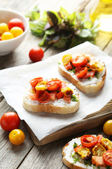 Tasty fresh bruschetta with tomatoes on cutting board on grey wo