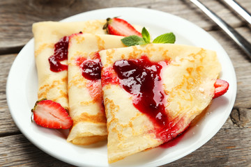 Pancakes with strawberry on plate on grey wooden backgound