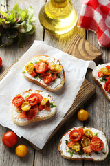 Tasty fresh bruschetta with tomatoes on cutting board on grey wo