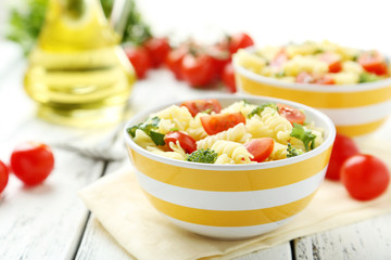 Delicious pasta in bowl on white wooden background