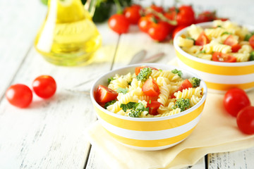 Delicious pasta in bowl on white wooden background