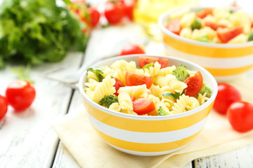 Delicious pasta in bowl on white wooden background