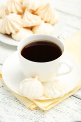 French meringue cookies with cup of coffee on white wooden backg