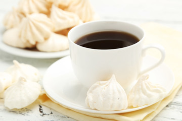 French meringue cookies with cup of coffee on white wooden backg