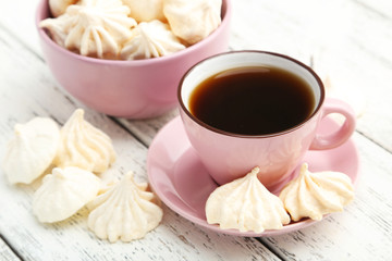 French meringue cookies with cup of coffee on white wooden backg