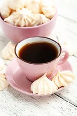 French meringue cookies with cup of coffee on white wooden backg