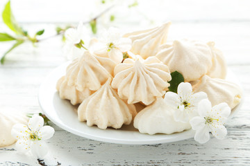French meringue cookies on plate on white wooden background - obrazy, fototapety, plakaty