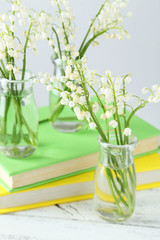 Lily of the Valley in bottles on white wooden background