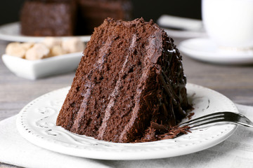 Delicious chocolate cake in white plate on wooden table background, closeup