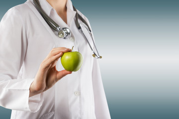 Female doctor's hand holding green apple isolated on white 