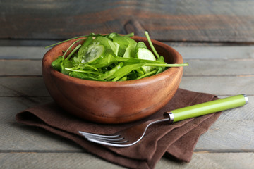 Green salad in bowl on wooden background