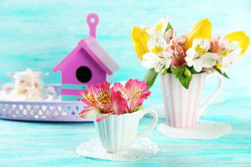 Beautiful flowers in cup, on color wooden background