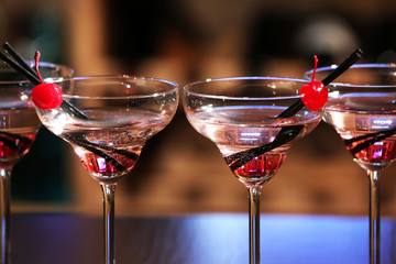 Glasses of cocktails on bar background