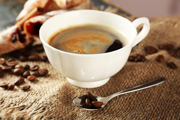 Cup of coffee with beans on table, closeup