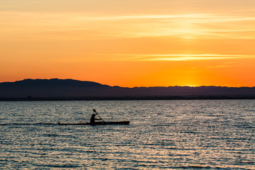Man canoeing on sunset
