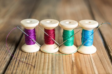 Spools of thread with needles on wooden background. Old sewing a