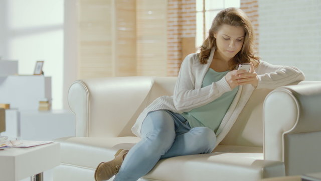 Beautiful girl typing message, chatting on smartphone at home