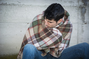 Young male beggar on city sidewalk