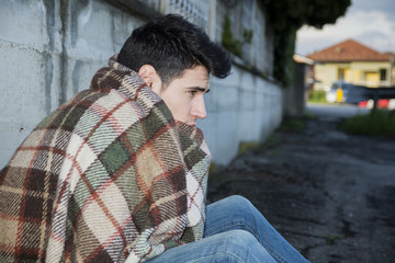 Young male beggar on city sidewalk