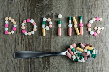 The word doping written with pills on a wooden background.