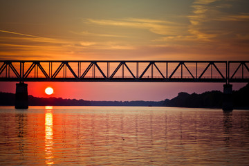 Naklejka na ściany i meble Sunset on the river with railway bridge.
