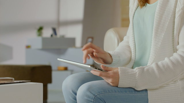 Female hands typing message, browsing internet on tablet at home