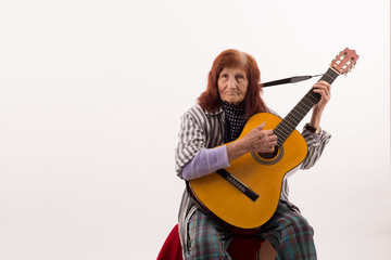 Funny elderly lady playing acoustic guitar.