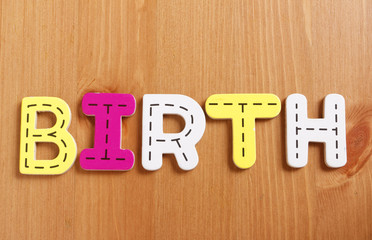 BIRTH, spell by woody puzzle letters with woody background