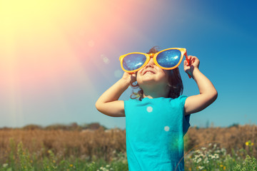 Little girl with big sunglasses enjoys sun