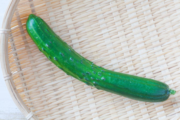 Fresh green cucumber in bamboo tray on white background