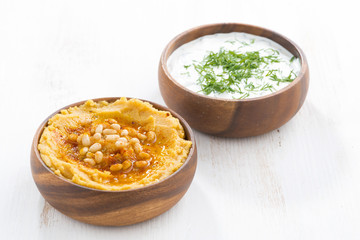 yoghurt sauce and hummus in bowls on wooden table
