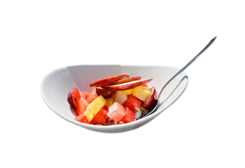 Fruit salad in plate with spoon isolated on white.