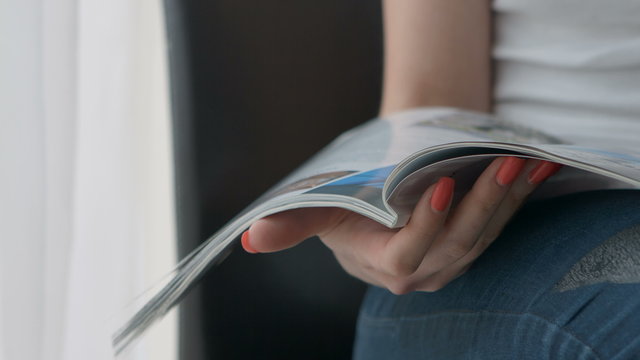 Woman Hands holding open holding magazine. Close up