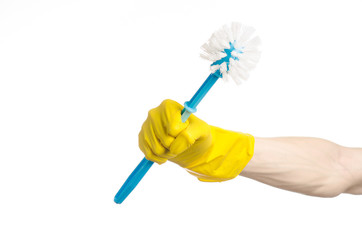 human hand holding a blue toilet brush in yellow gloves