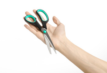 human hand holding a black scissors with blue accents in studio