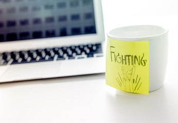 Note and post-it on cup of coffee with laptop