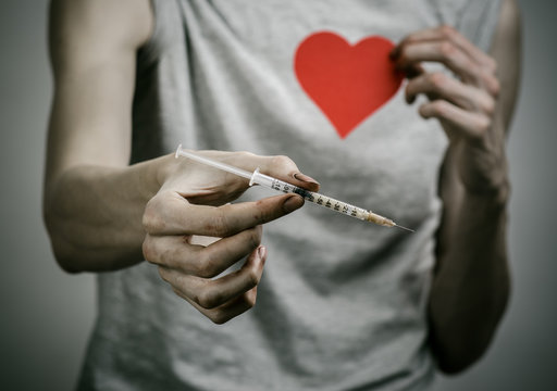 skinny dirty addict holding a syringe with a drug and red heart