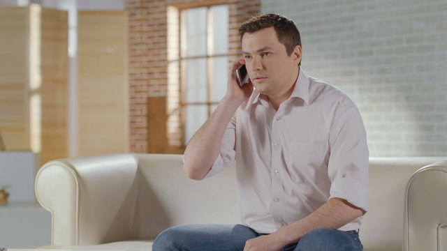 Young man discussing business problems in phone call at home