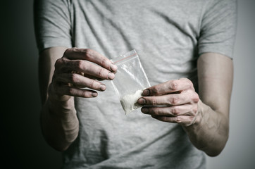 addict holding package of cocaine in a gray shirt  in the studio