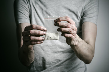 Fototapeta premium addict holding package of cocaine in a gray shirt in the studio