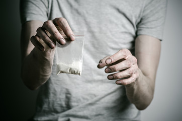 addict holding package of cocaine in a gray shirt  in the studio