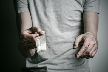 addict holding package of cocaine in a gray shirt  in the studio