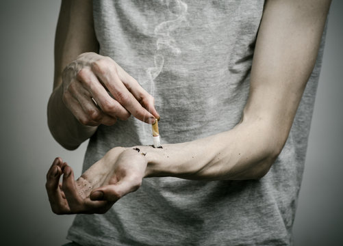 smoker puts his hand on the cigarette on a dark background