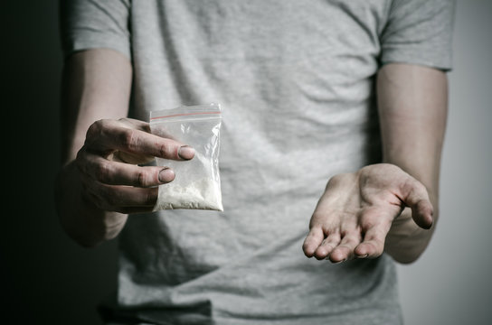 addict holding package of cocaine in a gray shirt  in the studio
