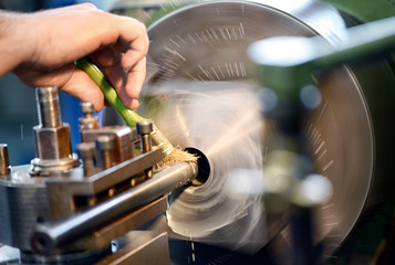 Man placing lubricating oil on a lathe