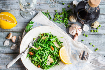 fresh green salad with arugula, cheese, almonds, lemon and olive